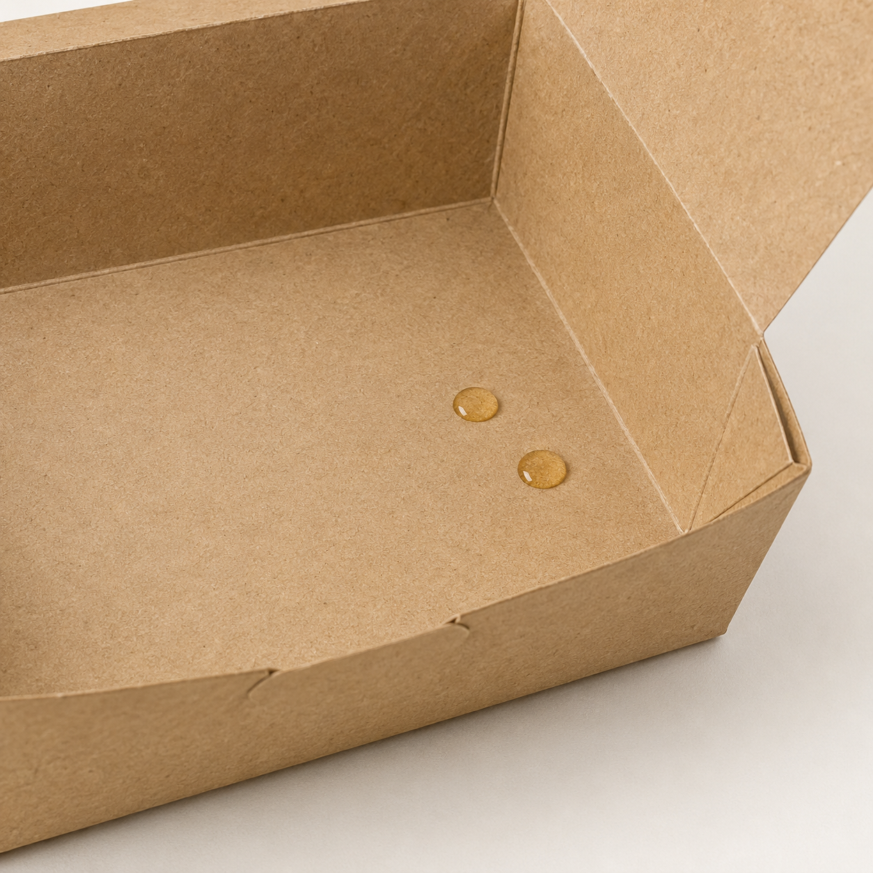 Kraft food box with oil droplets beading on its coated interior.