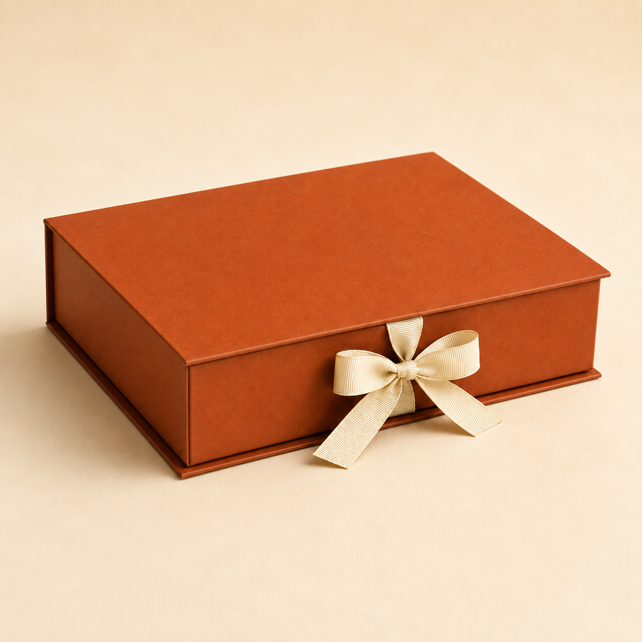 Burnt-orange rigid box secured by a front ribbon bow closure.