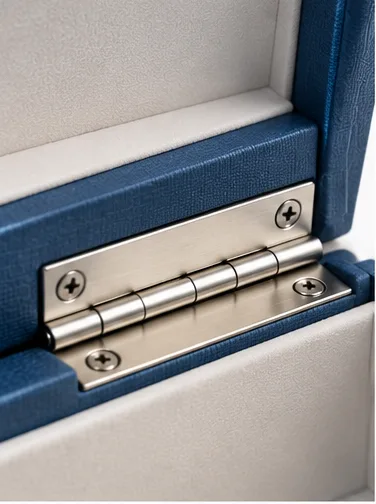 Close-up of the defined metal hinge that creates the pivot between the lid and base of a hinged rigid box.