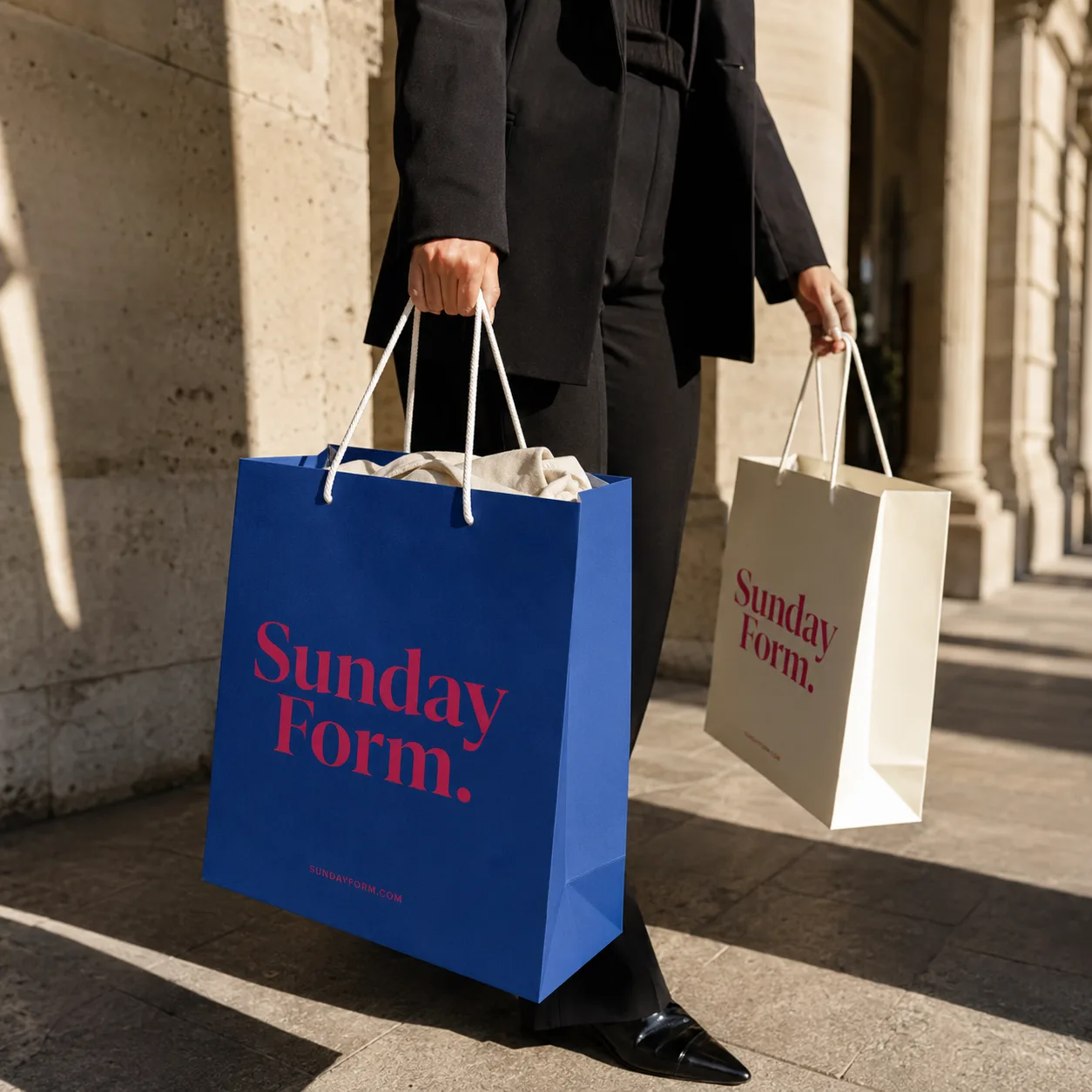 Apparel paper bags with rope handles held by shopper on bench