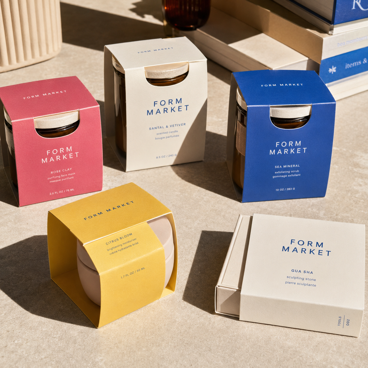 Retail packaging sleeve boxes wrapped around jars, shown in pink, cream, blue, and yellow with a cut-out window revealing the jar lid.