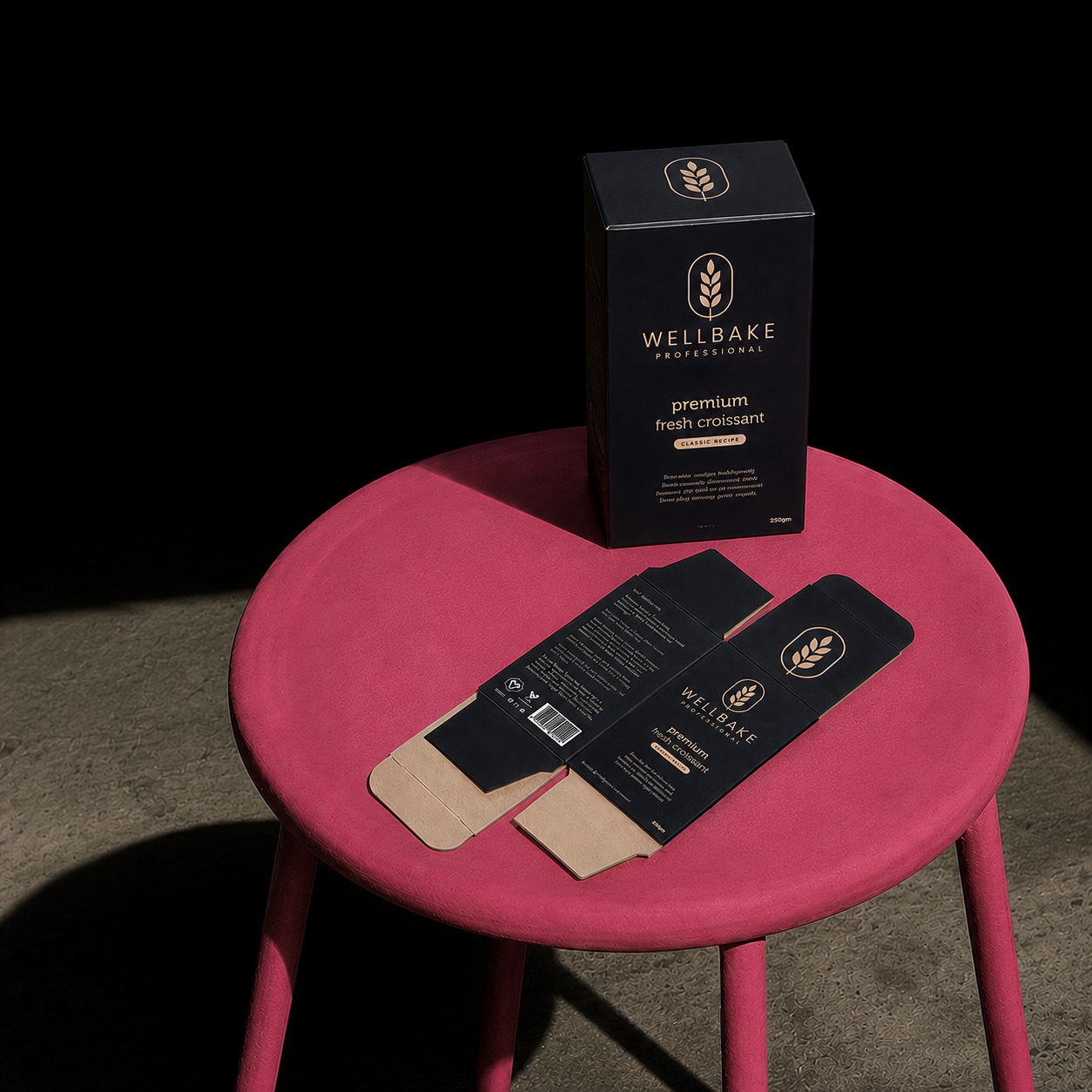 Custom reverse tuck box in matte black with gold wheat emblem, shown upright and flattened/unfolded on a pink stool.